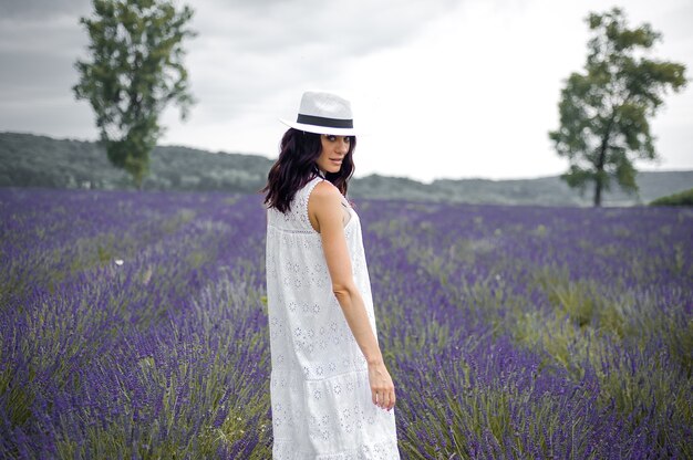 Mooie sensuele jonge vrouw met hoed en witte jurk op het lavendelveld