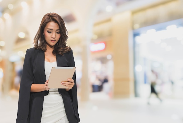 Mooie sexy Aziatische onderneemster die tablet in winkelcomplex gebruikt