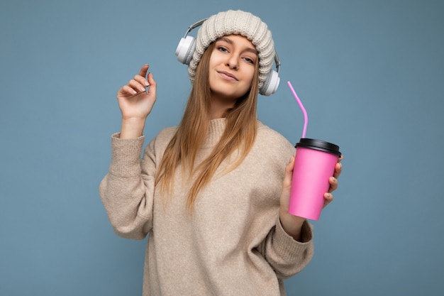 Mooie sexy positieve glimlachende jonge blonde vrouw, gekleed in beige winter trui en hoed geïsoleerd