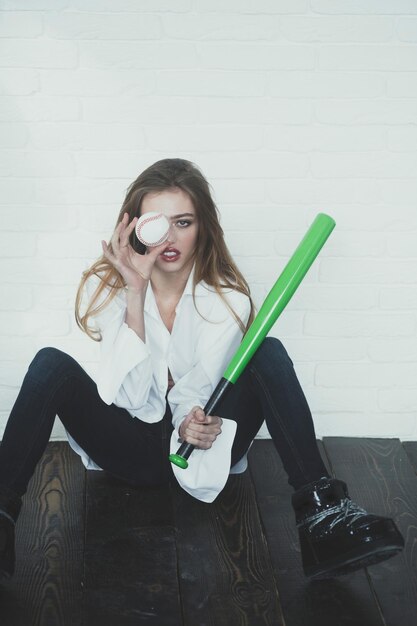 Mooie sexy vrouw met lang haar houdt groene honkbalknuppel vast