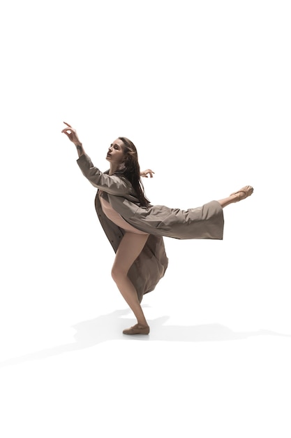Mooie slanke jonge vrouwelijke moderne jazz hedendaagse stijl balletdanser in silhouet dragen beige lange mantel geïsoleerd op een witte studio background