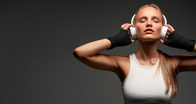 Mooie slanke meid luistert naar muziek via je draadloze koptelefoon voordat ze in de sportschool gaat trainen