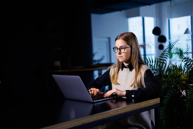 Mooie slimme aantrekkelijke elegante vrouw zakenvrouw in een groot bedrijf houdt een online vergadering met internationale zakenpartners, ze zit aan een tafel op de werkplek met een laptop