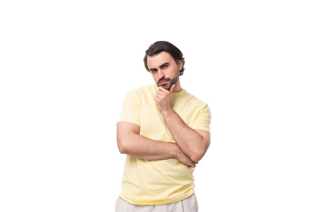 Mooie slimme jonge blanke man met zwart haar en baard in een lichtgeel t-shirt