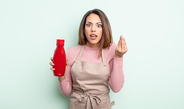 Mooie Spaanse vrouw die capice of geldgebaar maakt en zegt dat je moet betalen. ketchup-concept