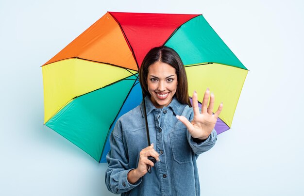 Mooie Spaanse vrouw die lacht en er vriendelijk uitziet, met nummer vijf. paraplu concept