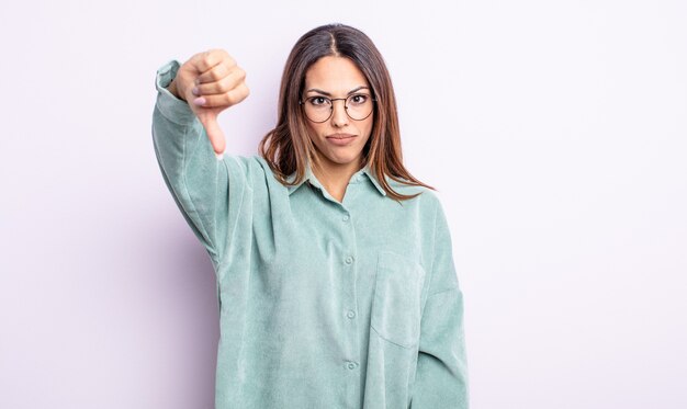 Mooie Spaanse vrouw die zich boos, boos, geïrriteerd, teleurgesteld of ontevreden voelt, duimen naar beneden met een serieuze blik