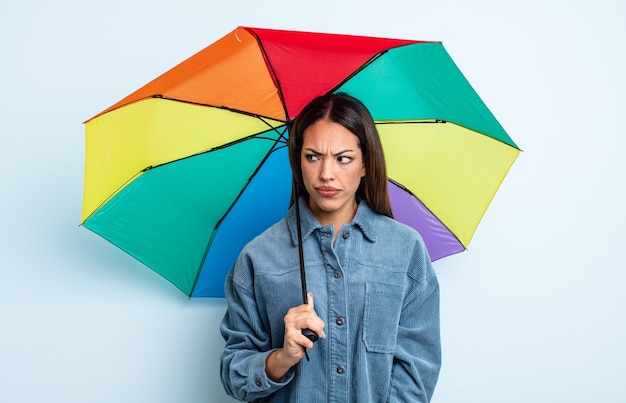 Mooie Spaanse vrouw die zich verdrietig, overstuur of boos voelt en opzij kijkt. paraplu concept