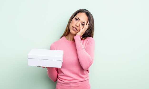 Mooie Spaanse vrouw die zich verveeld, gefrustreerd en slaperig voelt na een vermoeiende witte doos verpakkingsconcept