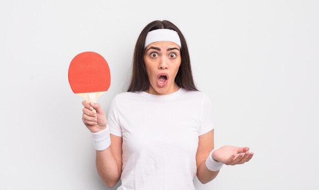 Mooie Spaanse vrouw verbaasd geschokt en verbaasd met een ongelooflijk verrassend pingpongconcept