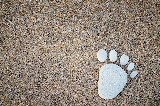 Mooie steen gemaakt voetafdruk op de zandkust. Achtergrondconcept van menselijk teken op de aarde. Voet van reiziger gemaakt van kiezelsteen. Ruimte kopiëren.