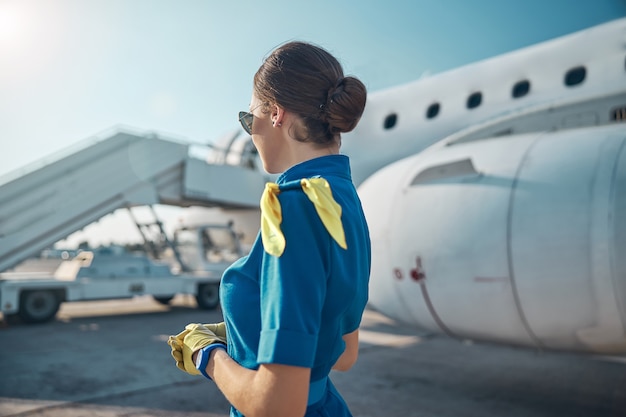 Mooie stewardess bereidt zich voor op de vlucht op zonnige dag