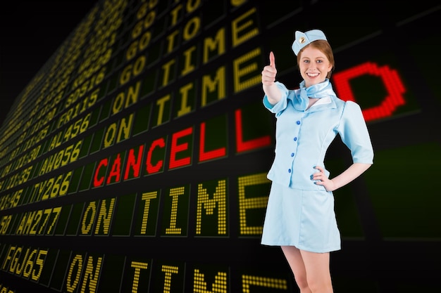 Mooie stewardess met de hand op de heup tegen het zwarte vertrekbord van de luchthaven