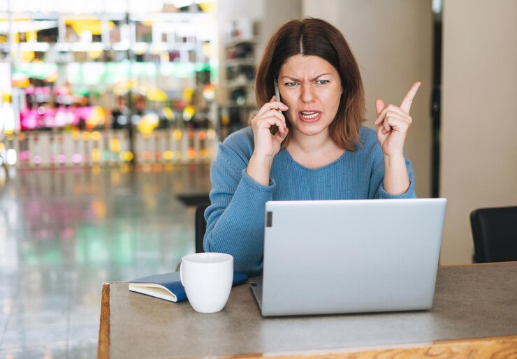Mooie stijlvolle jonge vrouw plus size lichaam positief schreeuwen over mobiele telefoon met behulp van laptop
