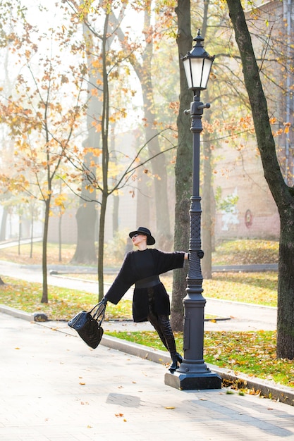 Mooie stijlvolle vrouw in een zwarte hoed in herfst park