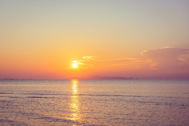 Mooie strandzonsondergang met blauwe overzees en gouden lichte hemelwolk