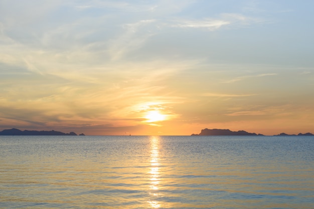 Mooie strandzonsondergang met blauwe overzees en gouden lichte hemelwolk