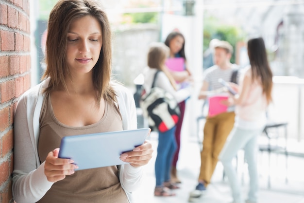 Mooie student die en tablet glimlacht houdt