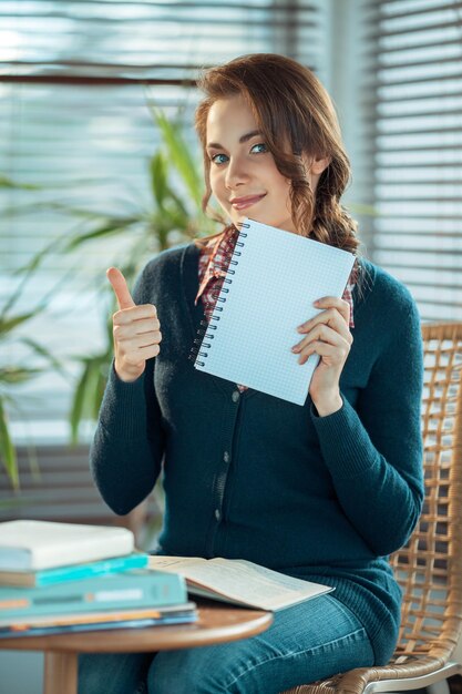 Mooie student duim opdagen en een leeg notitieboekje