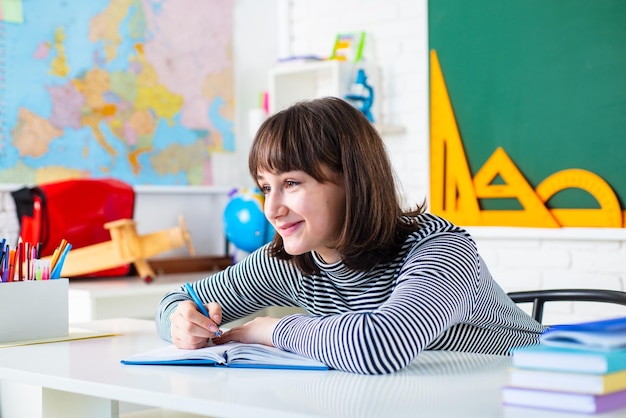 Mooie student meisje in de klas Portret van vrouwelijke universiteitsstudent binnenshuis Gelukkig casual studente met over schoolbord achtergrond Student