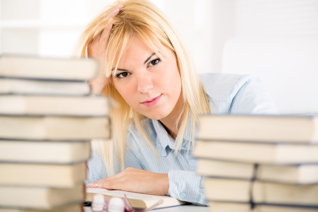 Mooie student meisje leren en denken tussen vele boeken.