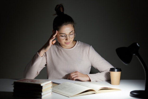 Mooie student zit aan wit bureau tegen dark