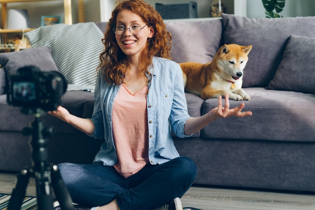 Mooie studente die video opneemt met hond voor internetvlog thuis