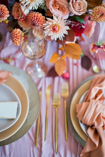 Mooie tafelsetting met herfstbloemen, oranje en roze servetten en brandende kaarsen Herfsthuwelijksconcept