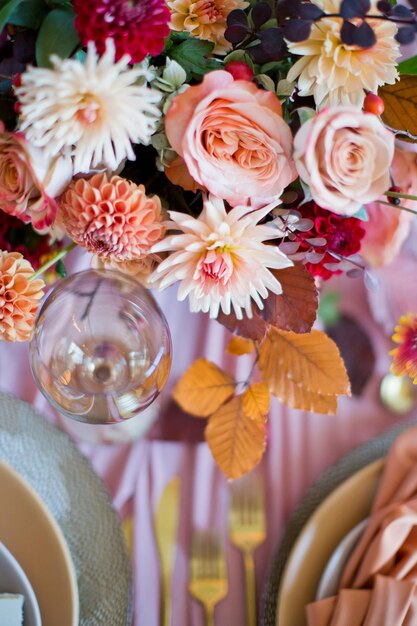 Mooie tafelsetting met herfstbloemen, oranje en roze servetten en brandende kaarsen Herfsthuwelijksconcept