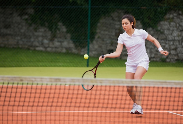 Mooie tennisspeler die bal raakt