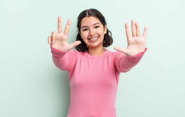 Mooie tienervrouw die lacht en er vriendelijk uitziet met nummer acht of achtste met de hand die naar voren aftelt