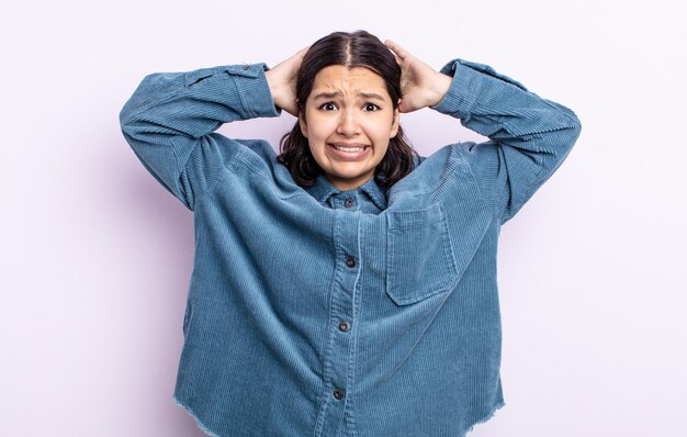 Mooie tienervrouw die zich gestrest, bezorgd, angstig of bang voelt, met de handen op het hoofd, in paniek bij vergissing