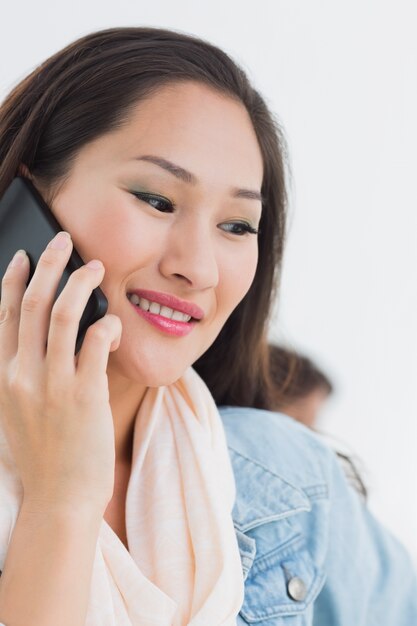 Mooie toevallige jonge vrouw die mobiele telefoon in bureau met behulp van