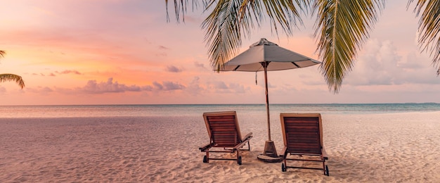 Mooie tropische eilandzonsondergang, paar ligbedden stoelen paraplu onder palmbladeren. wit zand