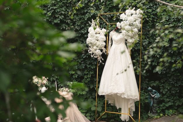 Mooie trouwjurk op een hanger, tafel, bloemen, tule op straat. De kosten van de bruid. Ochtend van de bruid
