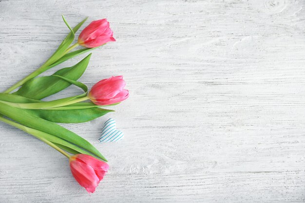 Mooie tulpen en klein katoenen hartje op licht houten