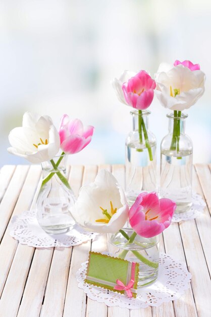 Mooie tulpen in emmer in vaas op tafel op lichte achtergrond
