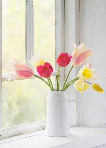 Mooie tulpen in vaas op witte vensterbank