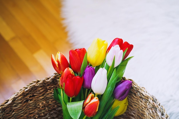 Mooie tulpen op achtergrond van interieur Lente bloemen boeket in rieten mand