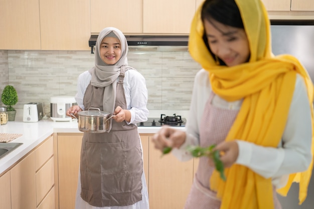 Mooie twee moslimvrouwen genieten van het samen koken van diner voor iftar die het vasten op ramadan in de keuken doorbreekt