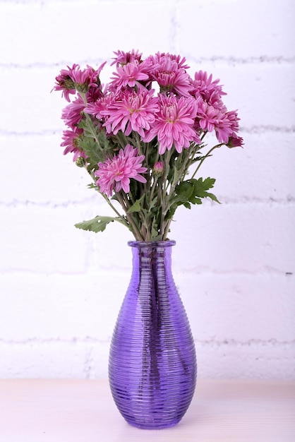 Mooie vaas met bloemen op de open haard in de kamer