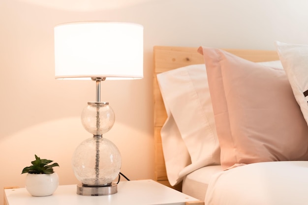 Mooie verlichte lamp met een kleine plant op een nachtkastje naast het bed