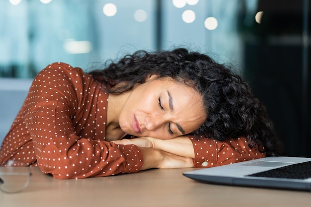 Mooie vermoeide Spaanse vrouw slapen op bureau close-up zakenvrouw met gesloten ogen dutten