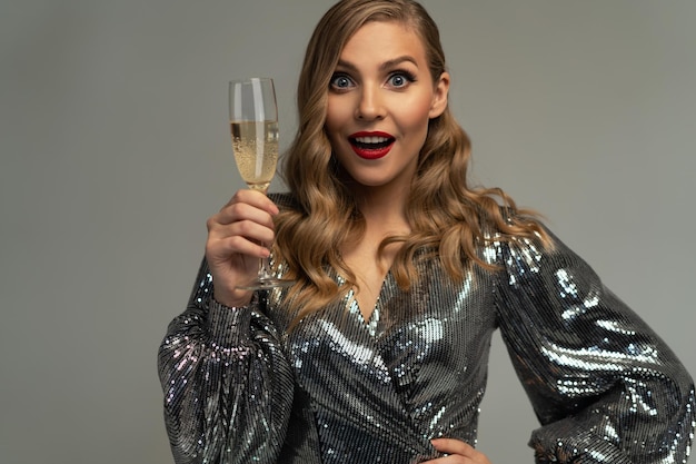 Mooie vierende vrouw met glas champagne en glimlachend geïsoleerd over studioachtergrond