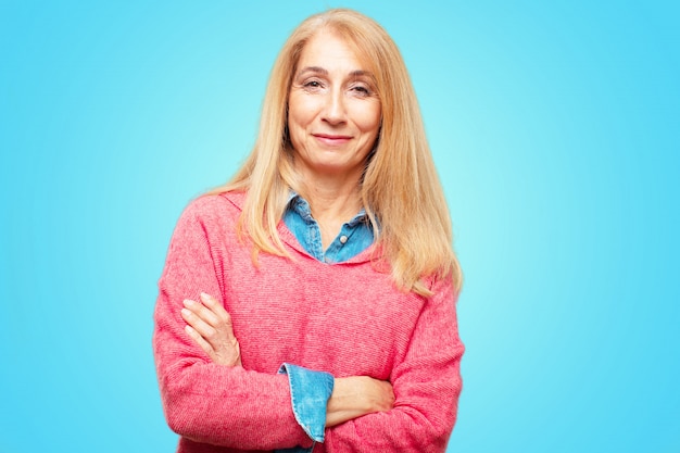 Mooie volwassen blonde vrouw met een trots, tevreden en gelukkig blik op het gezicht, lachend met armen oversteken