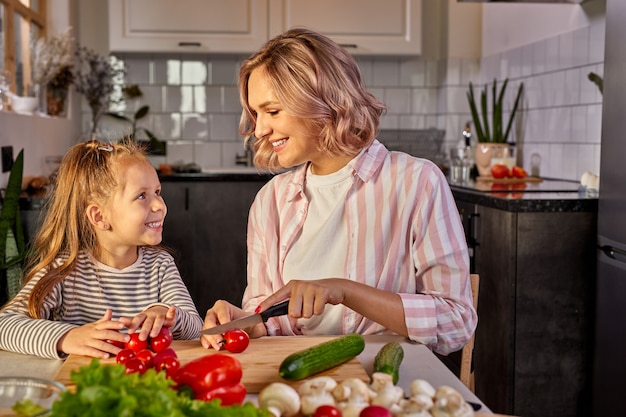 Mooie volwassen moeder en dochter gaan samen verse salade bereiden, met groenten. eten, familieconcept