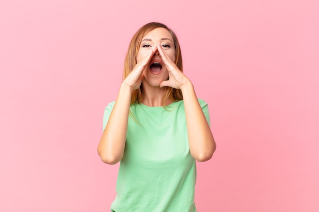 Mooie volwassen vrouw die zich gelukkig voelt en een grote schreeuw geeft met de handen naast de mond