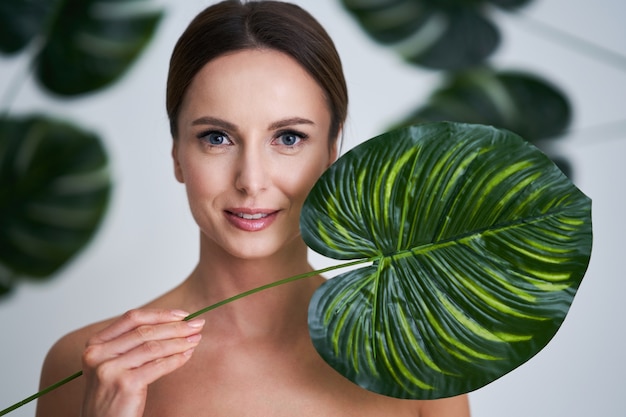 mooie volwassen vrouw poseren tegen blad achtergrond