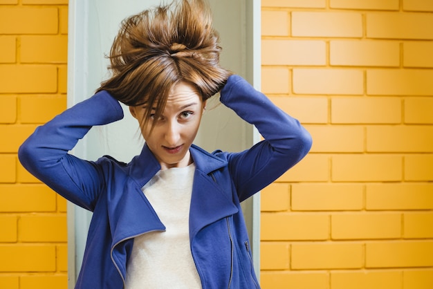 Mooie vrolijke moderne gekke vrouw op gele bakstenen muur