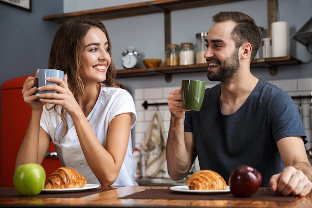 Mooie vrolijke paar ontbijten in de keuken